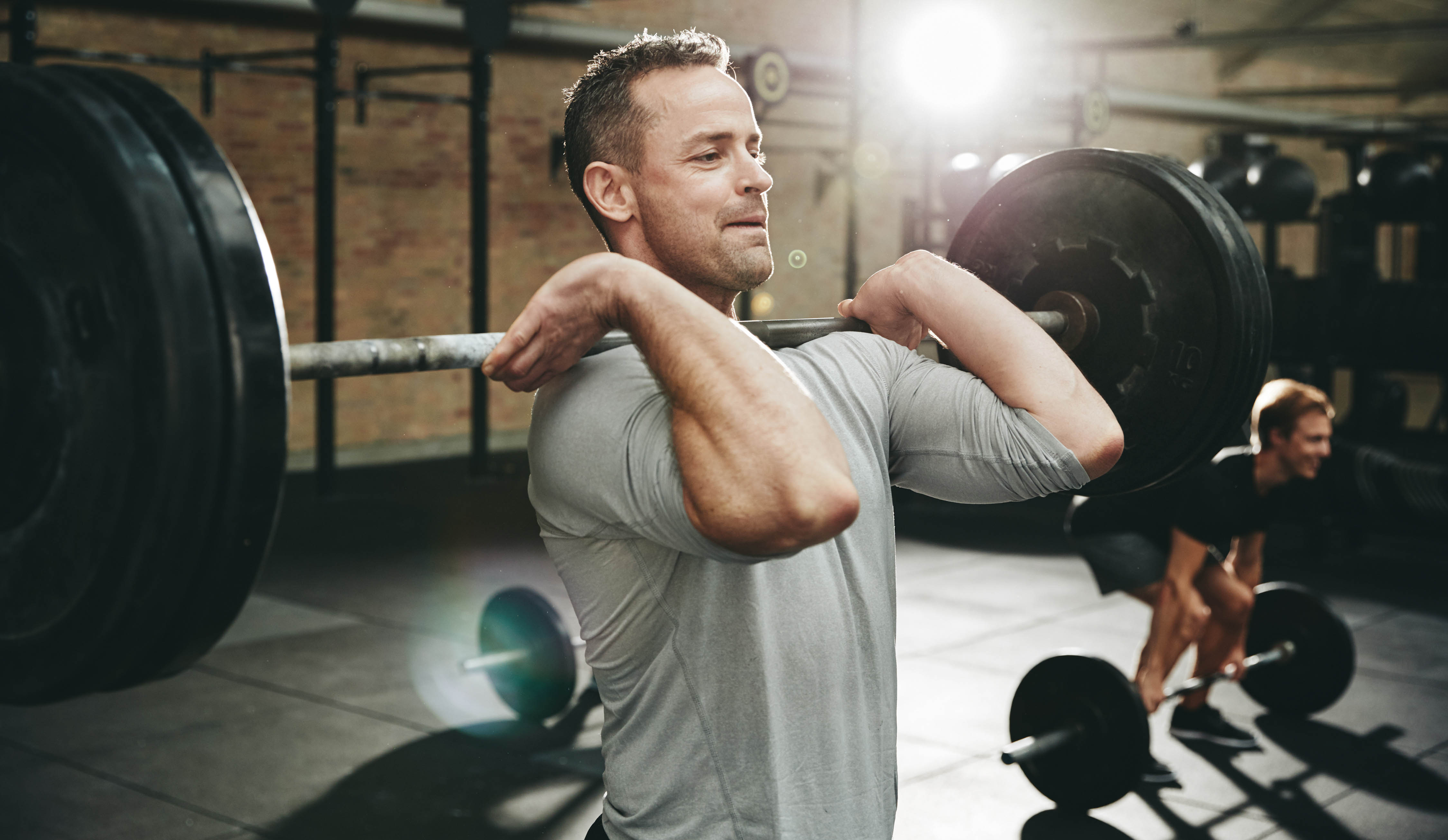 Fit young man, lifting weights in a group fitness class at the gym